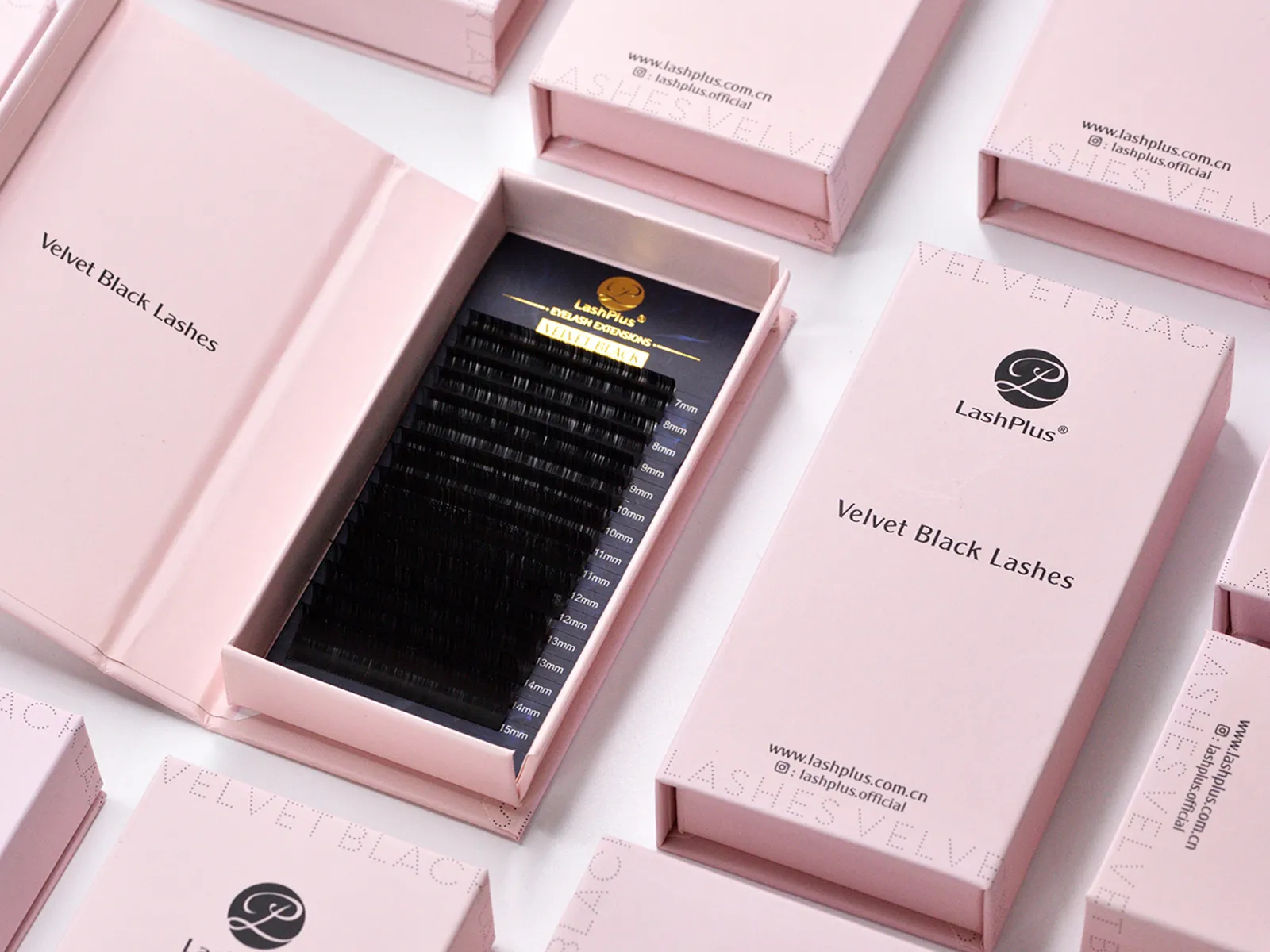 A pink magnetic rigid lash box opened to show a black velvet lash tray and a foil-stamped logo